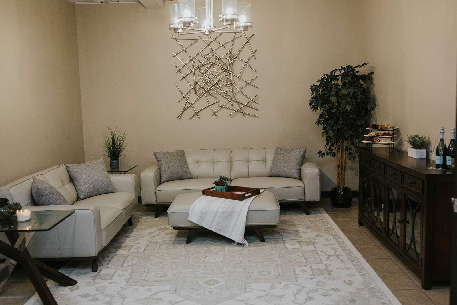 Elegant living room with modern decor, beige sofas, and a stylish geometric wall piece.