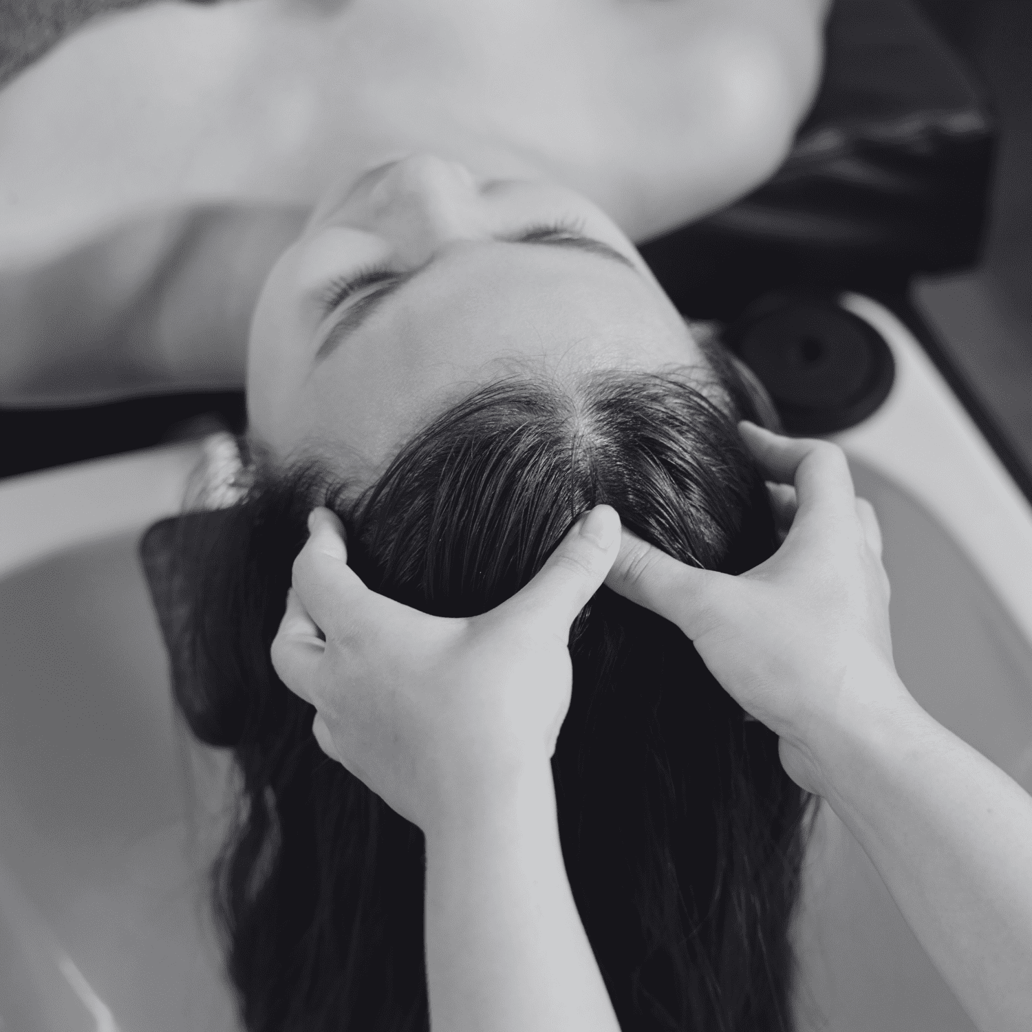 Woman receiving scalp massage in a salon setting.