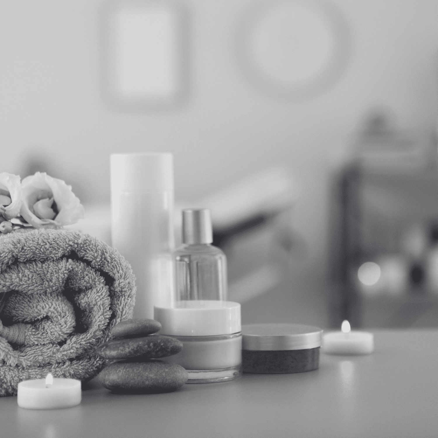 Spa essentials: towel, candles, lotion, and pebbles in a tranquil setting.